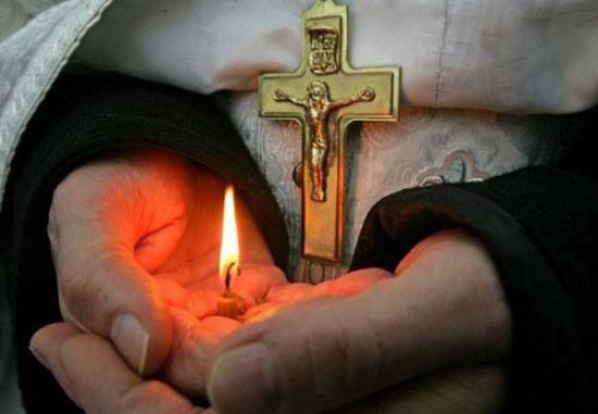 Religieux, croix et bougie dans la main